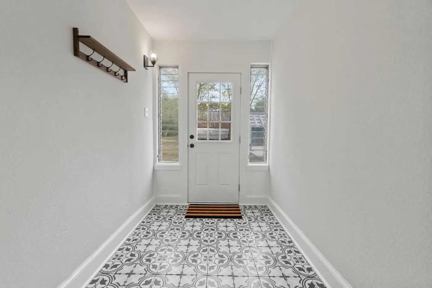 Entry hall with new patterned tile floor, white walls and a glazed front door