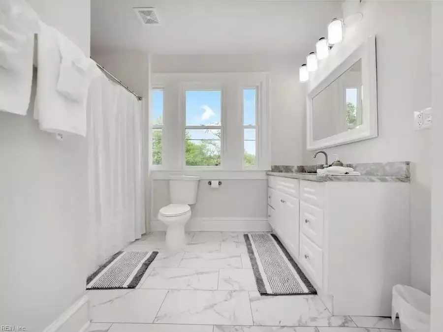 Primary bathroom with a walk-in shower, marble-look tile and a white vanity