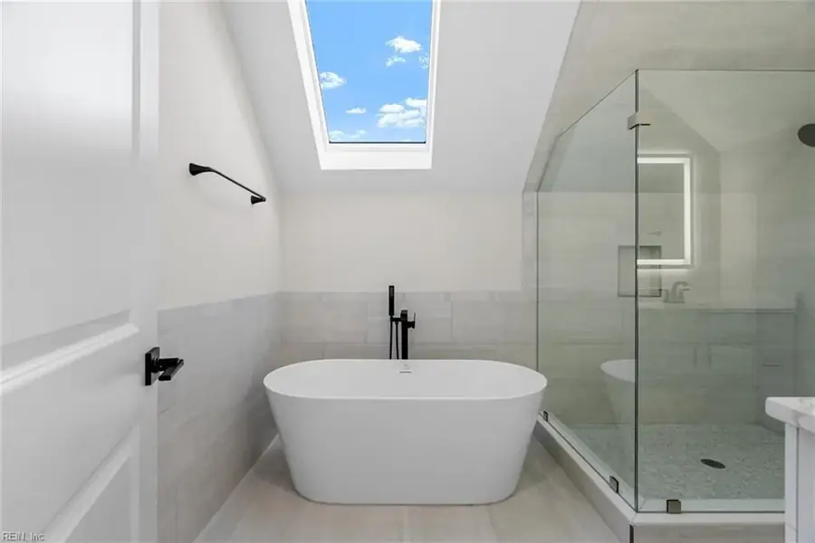 Bathroom renovation with glass shower, freestanding tub and marble-look tile