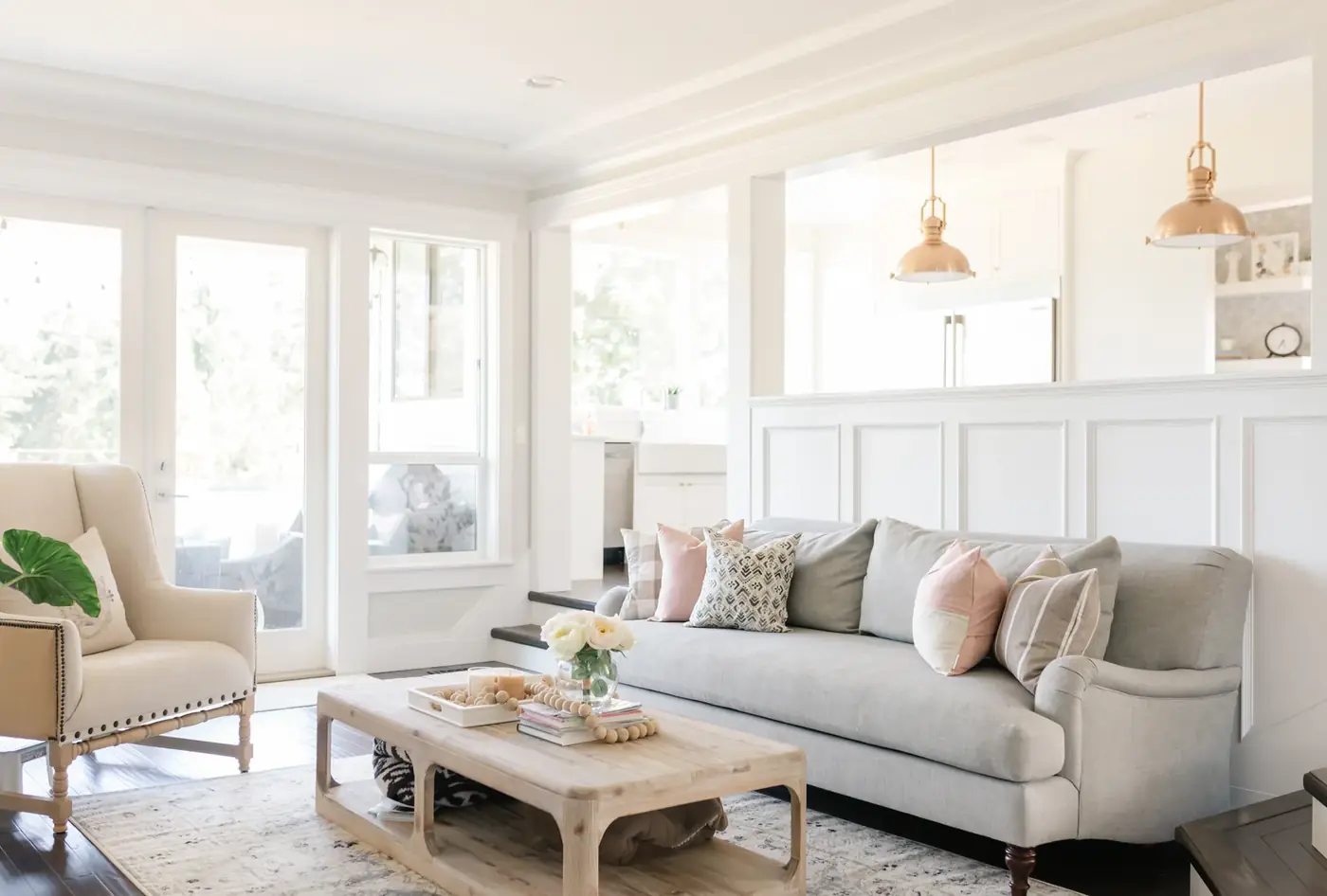 Bright living room with panelled walls and brass pendants, open to the kitchen after a whole-home renovation