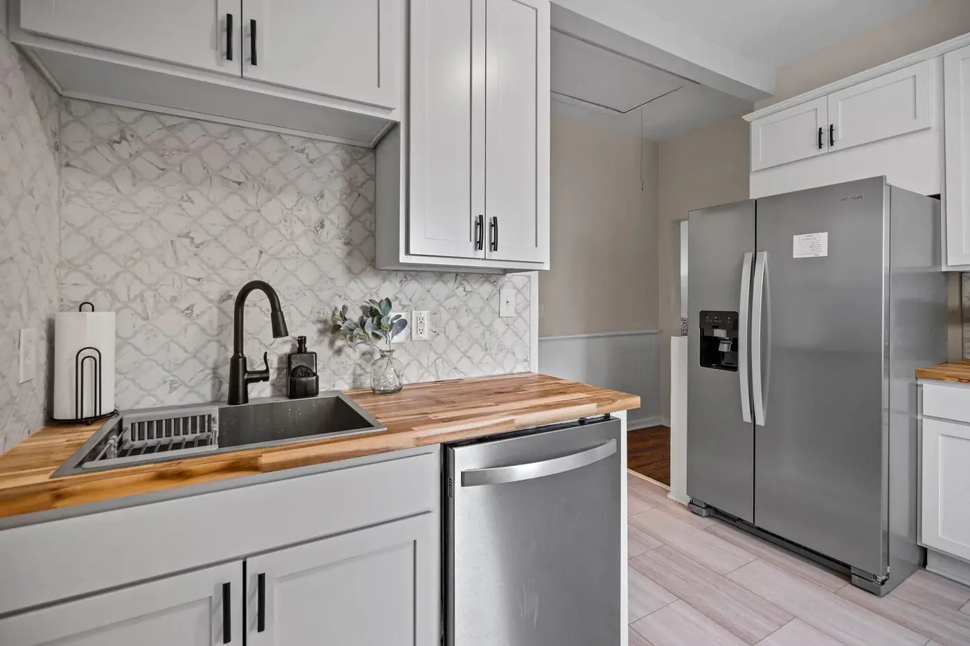 Kitchen sink wall with butcher-block counter, tiled backsplash and shelving