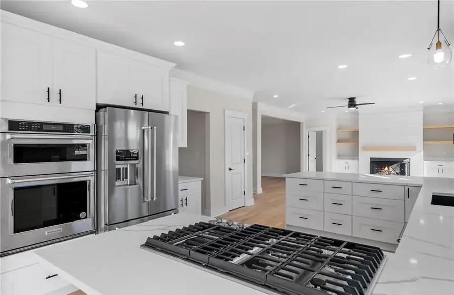 Two-tone kitchen with white cabinetry, wall ovens and a gas cooktop