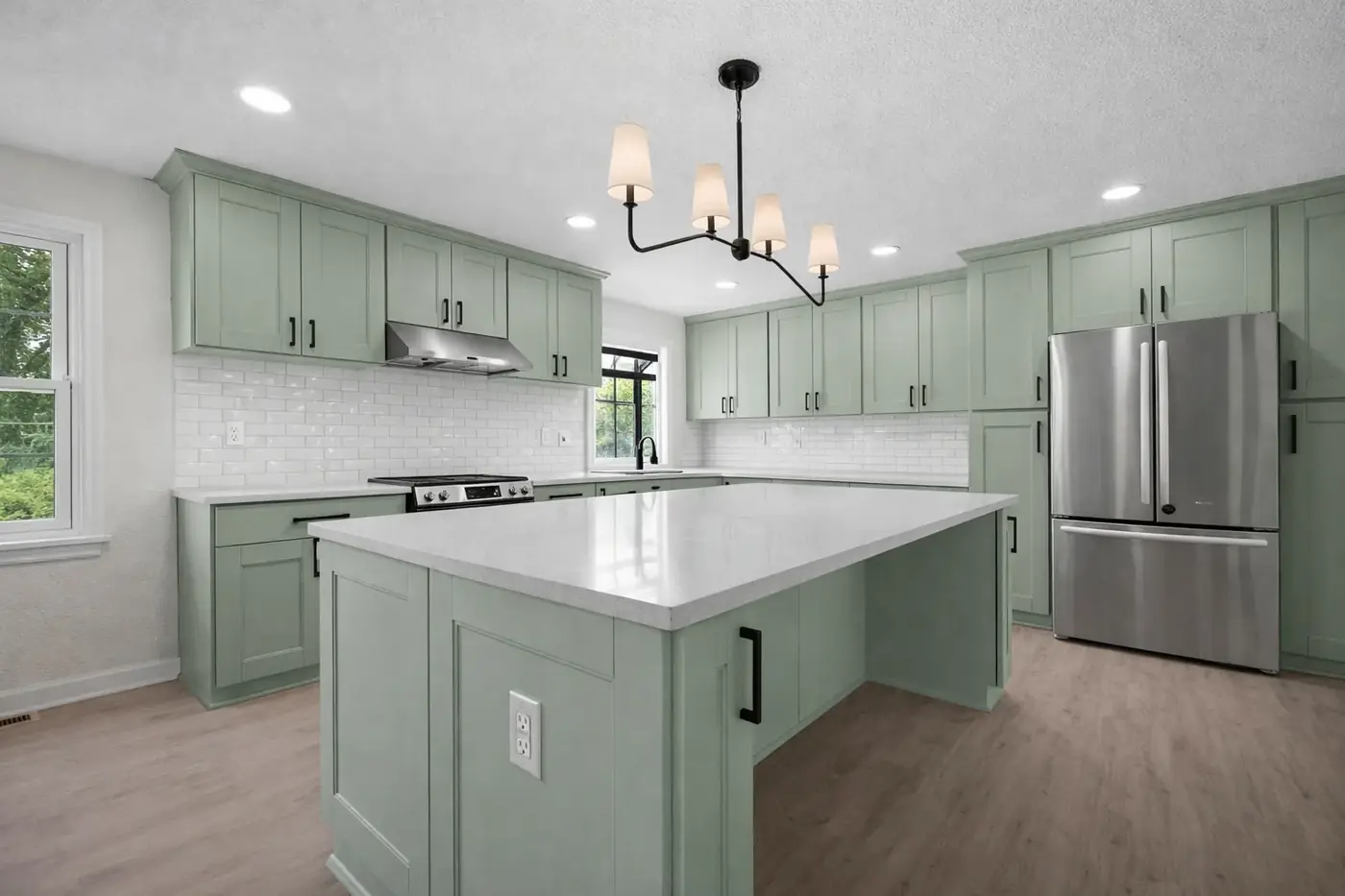 Kitchen renovation with sage-green cabinetry, a white quartz island and a black pendant fitting