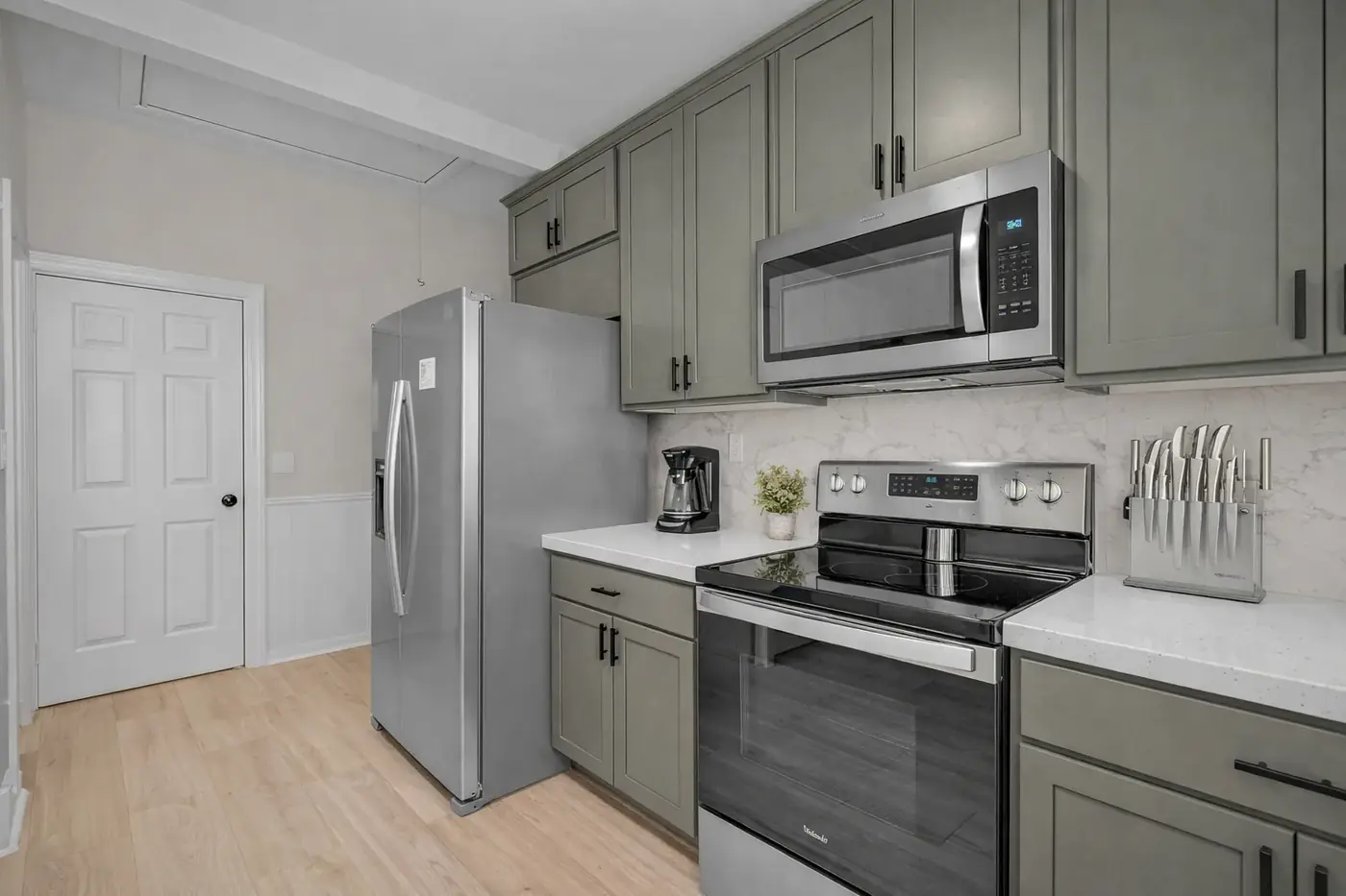 Sage kitchen with island seating, quartz counters and stainless appliances