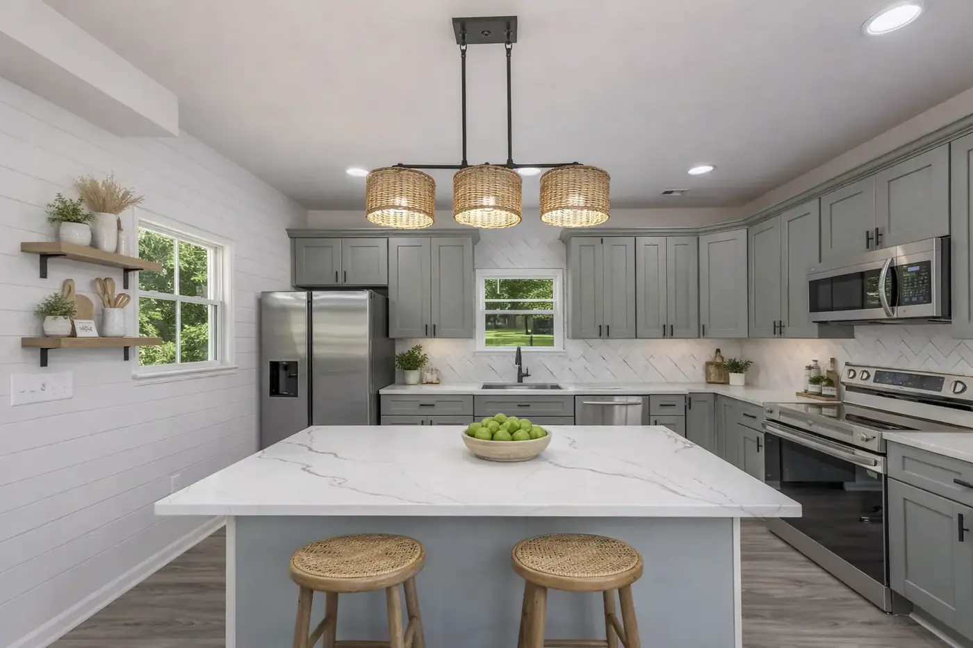 Renovated kitchen with white perimeter cabinetry, green island and brass pendants