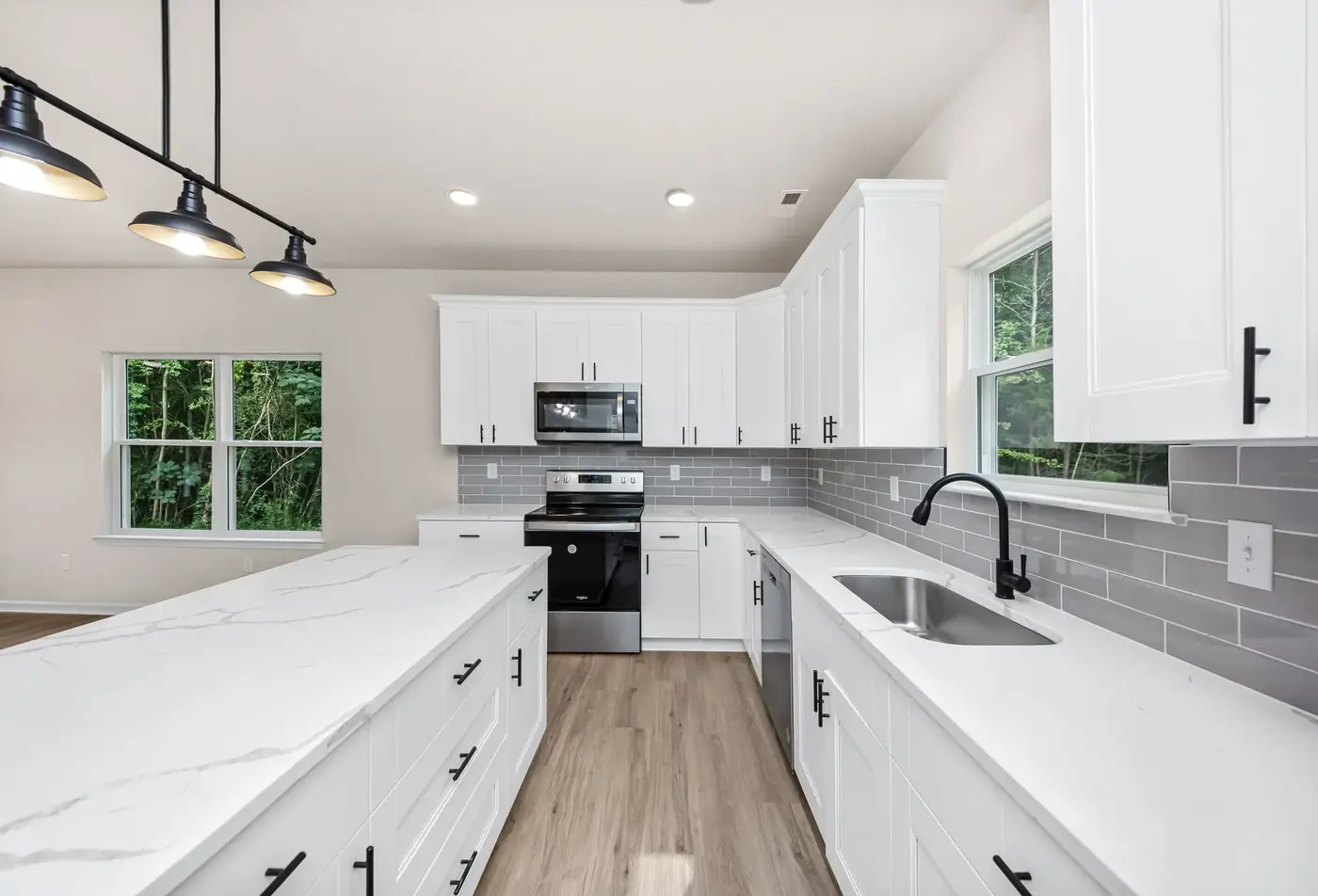 Renovated kitchen with white cabinetry, quartz counters and a large island