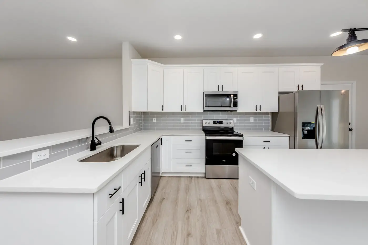 Kitchen with island, quartz counters and pendant lighting nearing completion