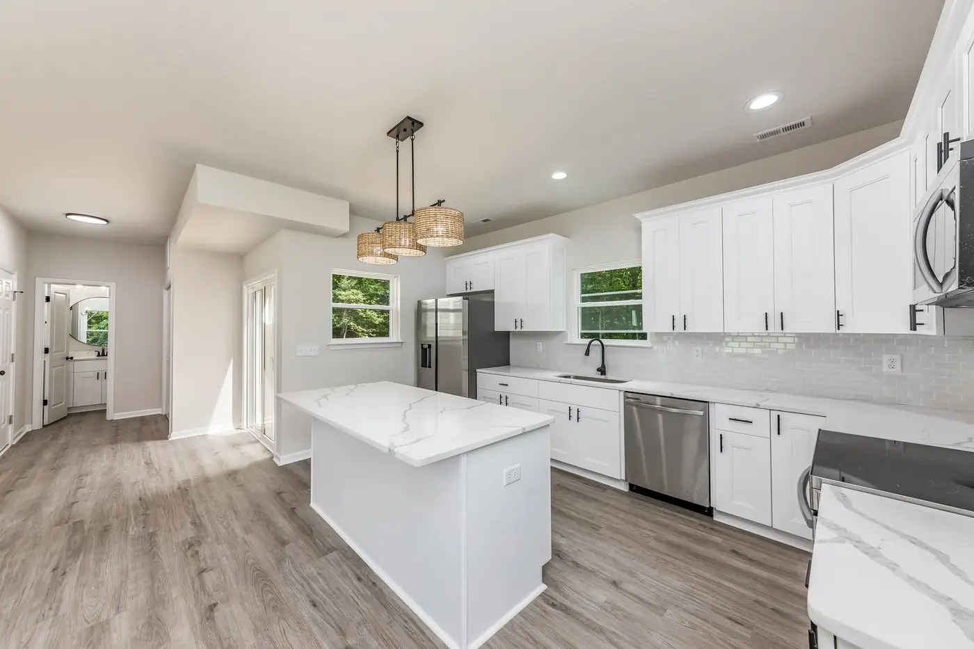 Renovated kitchen with white cabinetry, quartz island and pendant lights